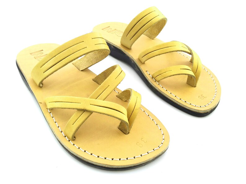 May include: A pair of tan leather sandals with multiple straps. The sandals have a simple design and are perfect for warm weather.