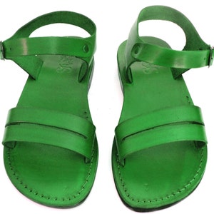 May include: A pair of green leather sandals with an ankle strap and a buckle closure. The sandals have a simple design and are made of high-quality leather.