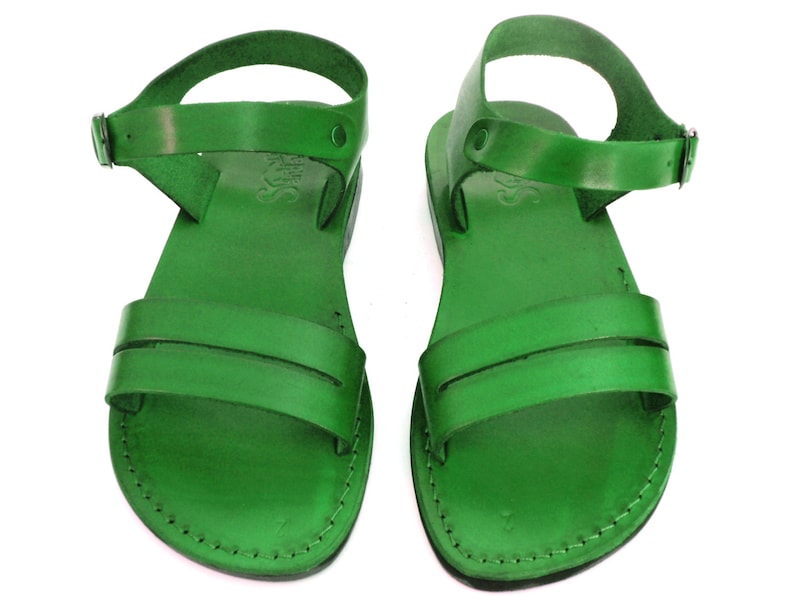 May include: A pair of green leather sandals with an ankle strap and a buckle closure. The sandals have a simple design and are made of high-quality leather.