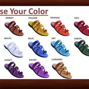 May include: A selection of colorful sandals, each with a floral accent. The image displays various colors, including brown, honey, yellow, orange, red, gray, black, white, blue, sky, green, apple, pink, violet, nahdi, and caramel. Text at the top reads "Choose Your Color."