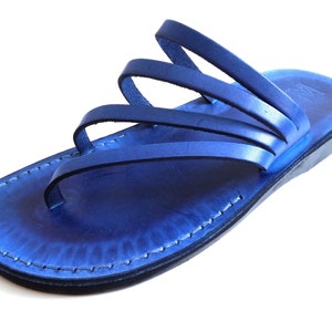 May include: Blue leather sandals with multiple straps. The sandals have a flat sole and a slightly raised heel.