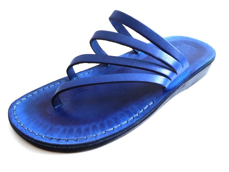 May include: Blue leather sandals with multiple straps. The sandals have a flat sole and a slightly raised heel.