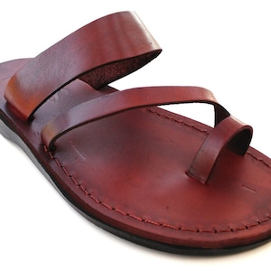 Peut inclure: Une paire de sandales en cuir marron avec une boucle d'orteil et deux lanières. Les sandales ont une semelle cousue et un design simple.