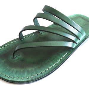 May include: Green leather sandals with multiple straps. The sandals have a simple design and are made of high-quality leather.