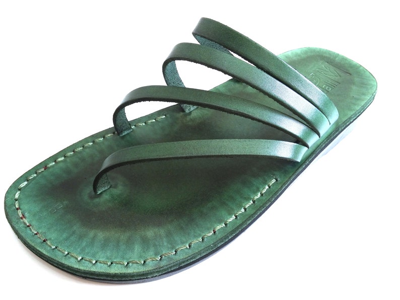 May include: Green leather sandals with multiple straps. The sandals have a simple design and are made of high-quality leather.