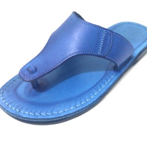 Peut inclure: Une paire de sandales en cuir bleu avec un design simple. Les sandales ont une seule sangle qui passe entre les orteils et un bord cousu.