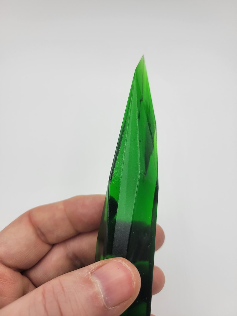 K&ouml;nnte beinhalten: Eine dunkelgr&uuml;ne Glaskristallspitze mit einer scharfen Spitze und einem facettierten Design.