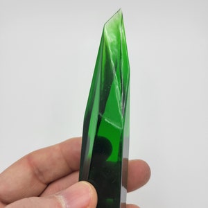 K&ouml;nnte beinhalten: Ein dunkelgr&uuml;ner Glaskristall mit einer spitzen Spitze und einer glatten, polierten Oberfl&auml;che.