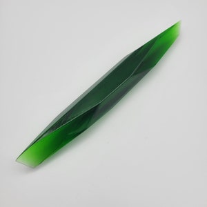 May include: A long, green, faceted glass rod with a pointed tip.