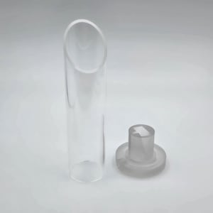 Op de afbeelding: Een heldere, cilindrische glazen buis met een schuine bovenkant, naast een matglazen stopper. De stopper heeft een cirkelvormige basis en een cilindrische bovenkant met een vierkant ontwerp. De objecten staan op een witte achtergrond.