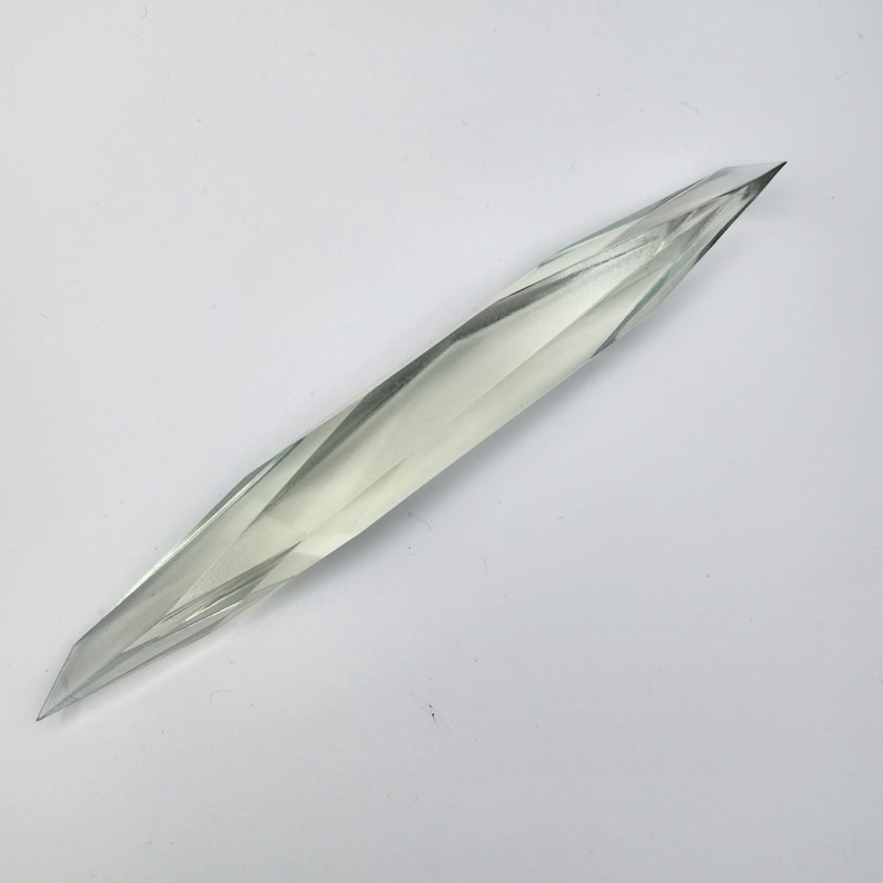 K&ouml;nnte beinhalten: Ein klares, facettierter, kristallartiger Gegenstand mit einer spitzen Spitze. Der Gegenstand ist lang und schlank und &auml;hnelt einem Dolch oder einem Schwert.