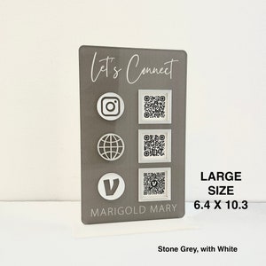 May include: A gray sign with the text "Let's Connect" and social media icons. The sign also includes QR codes for Instagram, a website, and a Venmo account. The text "MARIGOLD MARY" is at the bottom of the sign. The sign is labeled "LARGE SIZE 6.4 X 10.3" and "Stone Grey, with White".