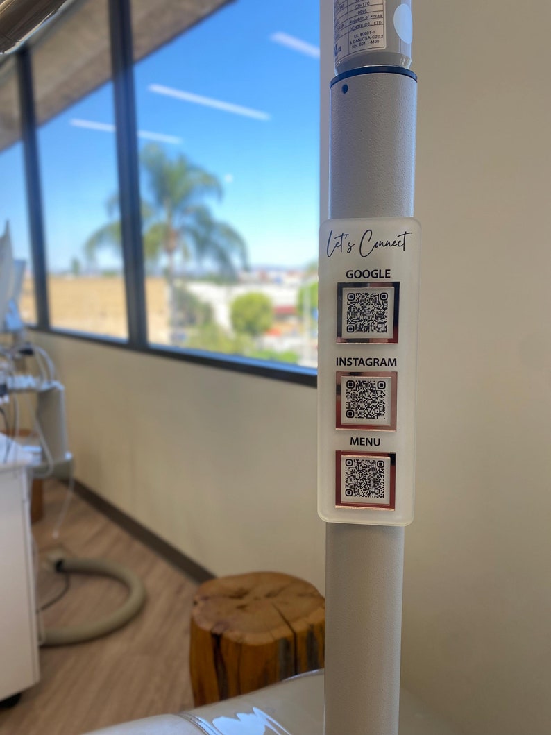 May include: A white pole with a sticker that says "Let's Connect" and has three QR codes labeled "Google", "Instagram", and "Menu".