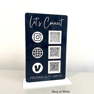 May include: A navy blue acrylic sign with white text that reads "Let's Connect". The sign features icons for Instagram, a website, and Venmo, each with a corresponding QR code. The sign also includes the name "PROVAN SLYS SMITH" and the text "Navy w/ White".