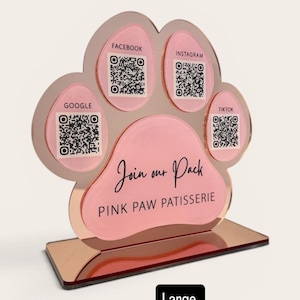 May include: A rose gold paw-shaped display with QR codes for Facebook, Instagram, Google, and TikTok. The text "Join our Pack" and "PINK PAW PATISSERIE" are displayed. The base reads "Large Rose Gold, with Cotton Candy."