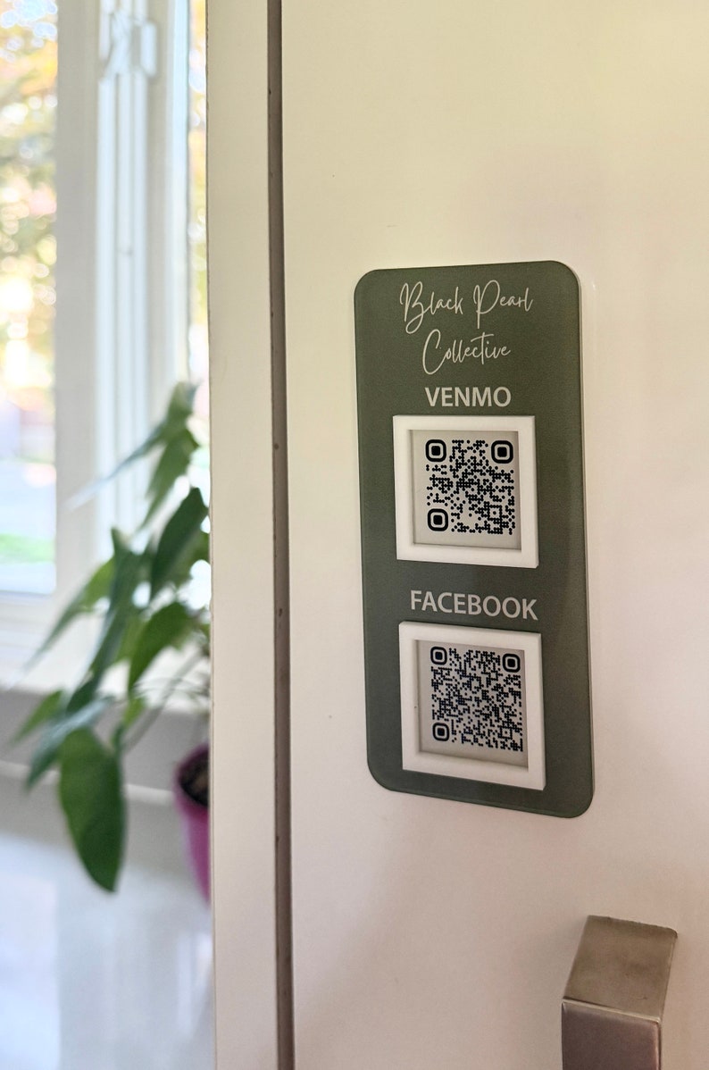 May include: A green sign with white text that reads "Black Pearl Collective" and has two QR codes. The top QR code is labeled "Venmo" and the bottom QR code is labeled "Facebook".