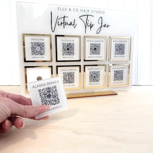 May include: A white acrylic sign with gold trim, displaying a virtual tip jar for a hair salon. The sign has eight square sections, each with a QR code and the name of a stylist. The text "ELLE & CO HAIR STUDIO" and "Virtual Tip Jar" are printed on the sign.