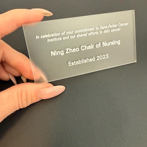 May include: A clear acrylic plaque with white text announcing the establishment of the Ning Zhao Chair of Nursing at the Dana-Farber Cancer Institute in 2023.
