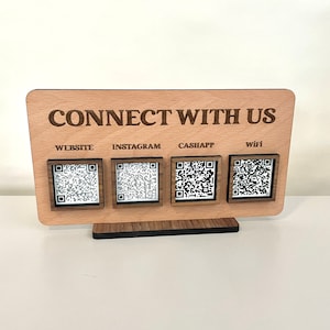 May include: Wooden sign with the text "CONNECT WITH US" and four QR codes labeled "WEBSITE", "INSTAGRAM", "CASHAPP", and "WIFI".