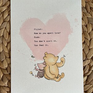 May include: A print featuring Winnie the Pooh and Piglet with a pink heart background. The text reads, "How do you spell love? You don't spell it. You feel it."