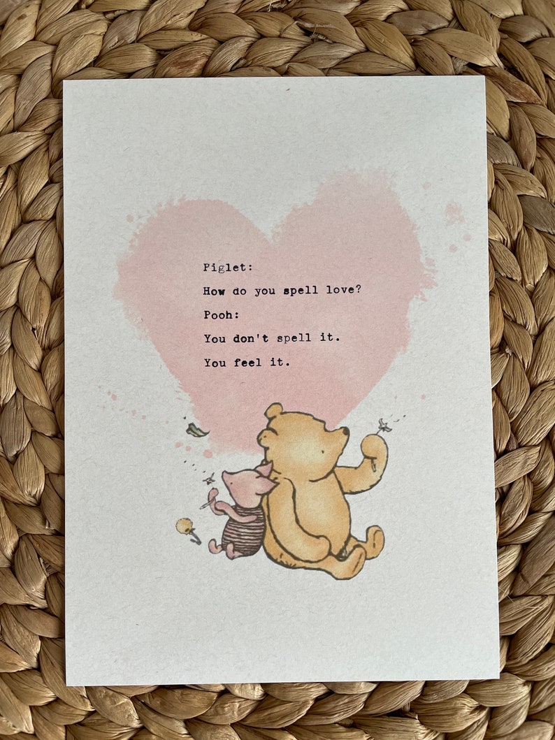 May include: A print featuring Winnie the Pooh and Piglet with a pink heart background. The text reads, "How do you spell love? You don't spell it. You feel it."