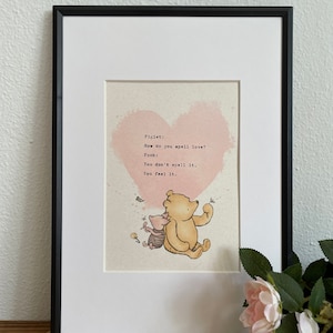 May include: Framed print featuring a quote from Winnie the Pooh with a pink heart background. The quote reads: "How do you spell love? You don't spell it. You feel it." The image includes illustrations of Pooh and Piglet.