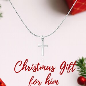 May include: A silver-toned chain necklace featuring a simple, smooth cross pendant. The text "Christmas Gift for him" is printed in red script below the pendant. The necklace is displayed against a light background with red and green accents.