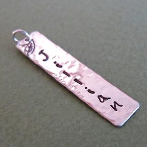 Puede incluir: Collar de barra de plata con acabado martillado y el nombre "Jillian" grabado en él.