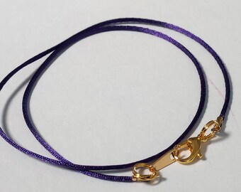 May include: A purple satin cord necklace with a gold clasp.