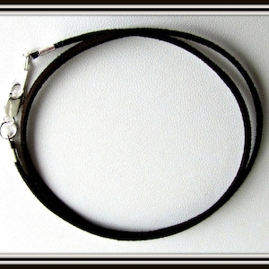 May include: A black leather cord necklace with a silver clasp.