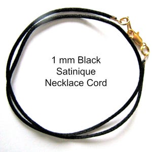 May include: A black satinique necklace cord, 1 mm thick, with a gold-colored clasp. The text "1 mm Black Satinique Necklace Cord" is printed on the image.