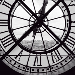 May include: A black and white photo of a large clock face with Roman numerals. The clock is set against a backdrop of a city skyline.