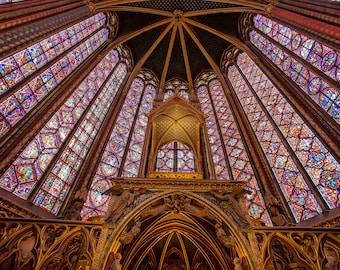 May include: A high-ceilinged chapel with stained glass windows in shades of red, blue, and purple. The windows are arranged in a radial pattern around a central point, creating a sense of awe and grandeur.