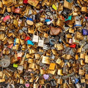 May include: A close-up of a wall covered in hundreds of colorful padlocks, many with engraved messages. The padlocks are attached to a metal grid, creating a dense, textured surface.
