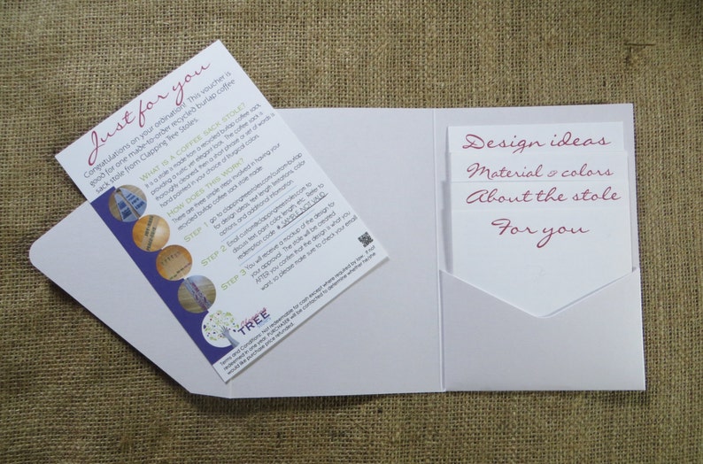 Pode incluir: Um envelope branco com um bolso no lado direito. O bolso cont&eacute;m tr&ecirc;s cart&otilde;es brancos com o texto "Design ideas", "Material & colors", "About the stole" e "For you" escrito em rosa. O lado esquerdo do envelope tem um cart&atilde;o dobrado com o texto "Just for you" e uma descri&ccedil;&atilde;o de uma estola de saco de caf&eacute;.