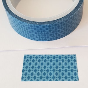 May include: A roll of blue decorative tape with a diamond pattern. A small rectangular piece of the same tape is shown below the roll. The tape has a light blue diamond pattern on a darker blue background.