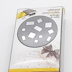 May include: A gray confetti punch with a round die featuring various sized square confetti shapes. The packaging is yellow with the text "confetti punch, poinçons à confettis, perforador de confetti".