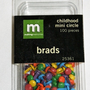 Może przedstawiać: Przezroczyste plastikowe opakowanie zawierające kolorowe mini brads w kształcie kółek. Czarna etykieta zawiera napis "childhood mini circle" i "100 sztuk". Brads są w różnych kolorach, takich jak czerwony, niebieski, zielony i żółty.