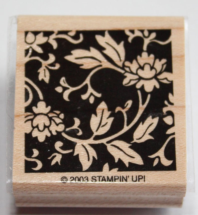 K&ouml;nnte beinhalten: Ein schwarzer und wei&szlig;er Gummistempel mit einem floralen Design. Der Stempel zeigt ein sich wiederholendes Muster aus Bl&auml;ttern und Blumen. Der Text "&copy; 2003 STAMPIN' UPI" ist auf der Unterseite des Stempels aufgedruckt.