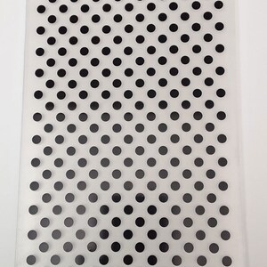 May include: A clear plastic sheet with a repeating pattern of black dots. The dots are arranged in a diagonal pattern.