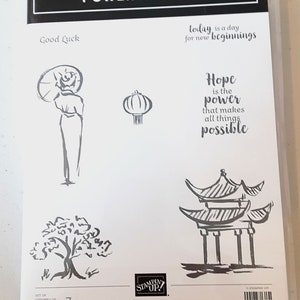 Puede incluir: Paquete de plástico transparente que contiene un juego de sellos de cling con el título "POWER OF HOPE". El conjunto incluye varias ilustraciones y frases de inspiración asiática, como "Good Luck" y "Hope is the power that makes all things possible."