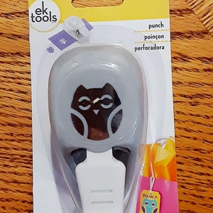 May include: A grey owl-shaped paper punch with a white handle. The packaging has the text "You are a Hoot" on a pink and yellow tag.
