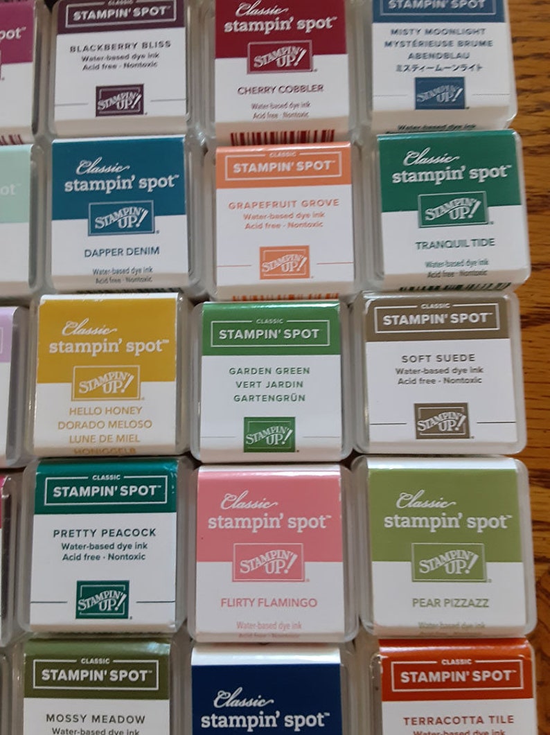 May include: A collection of 12 ink pads in various colors, each labeled "Classic stampin' spot" with the Stampin' Up! logo. The ink pads are arranged in three rows of four. The ink pad colors include Blackberry Bliss, Cherry Cobbler, Misty Moonlight, Dapper Denim, Grapefruit Grove, Tranquil Tide, Hello Honey, Garden Green, Soft Suede, Pretty Peacock, Flirty Flamingo, Pear Pizzazz, Mossy Meadow, and Terracotta Tile.