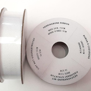 May include: White herringbone ribbon spool with text in English, French, Dutch, German, Spanish, and Portuguese. The ribbon is 3/4 inch wide and approximately 10 yards long.