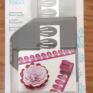 May include: A gray ek tools dimensional flower punch in a clear plastic package. The package shows examples of dimensional flowers in pink and red. The text "create dimensional flowers" is visible.