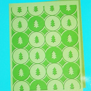 May include: A green and white patterned paper with a repeating design of Christmas trees inside circles.