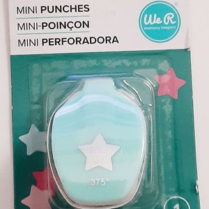 May include: A light blue mini star punch with a white star cutout. The punch is packaged in a clear plastic bag with a green and white label that reads "We R memory keepers" and "MINI PUNCHES MINI-POINÇON MINI PERFORADORA". The label also includes the size of the punch: "0.375 IN (9.53 CM)".