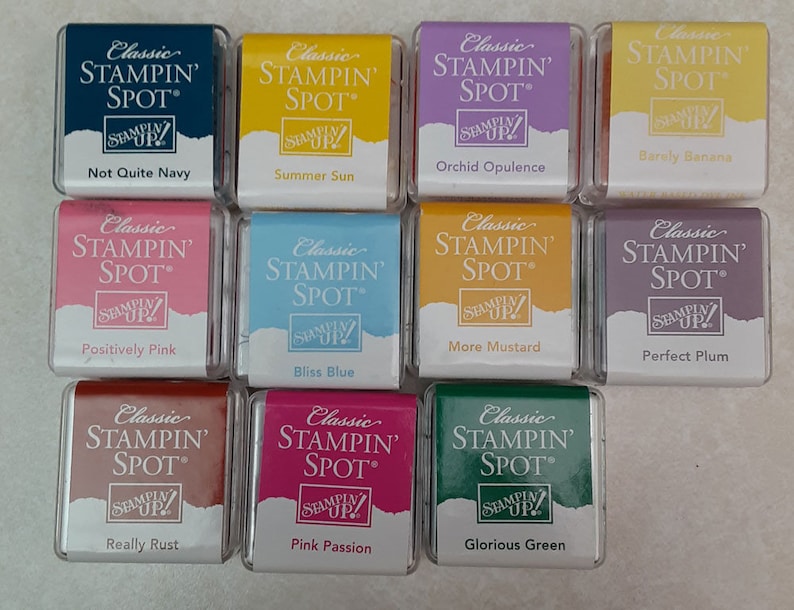 May include: Twelve small ink pads in various colors, including navy blue, yellow, purple, orange, pink, blue, yellow, purple, brown, pink, red, and green. Each pad has the words "Classic Stampin' Spot" printed on the front.