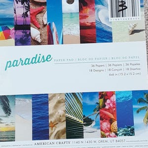 May include: A paper pad with the word "paradise" in a teal script. The pad features 36 sheets with 18 designs, each 6x6 inches. The designs include beach scenes, waves, and tropical elements.