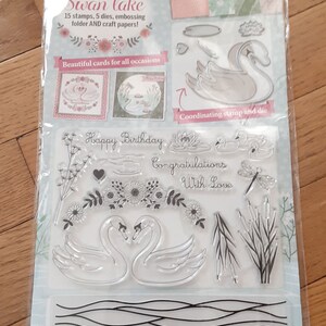 May include: A set of clear stamps featuring swans, flowers, water, and the text "Happy Birthday" and "Congratulations with Love". The stamps are designed for cardmaking and scrapbooking.